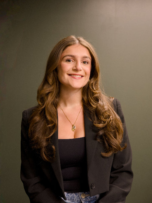 Woman with long brown hair wearing a black blazer against a gray background, LinkedIn headshots Guelph