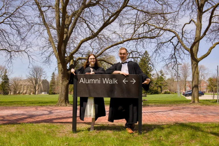 A graduate walking across campus by Johnston Green