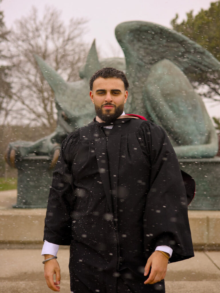 A graduate photographed by the historic stone buildings of the University of Guelph in the colder months