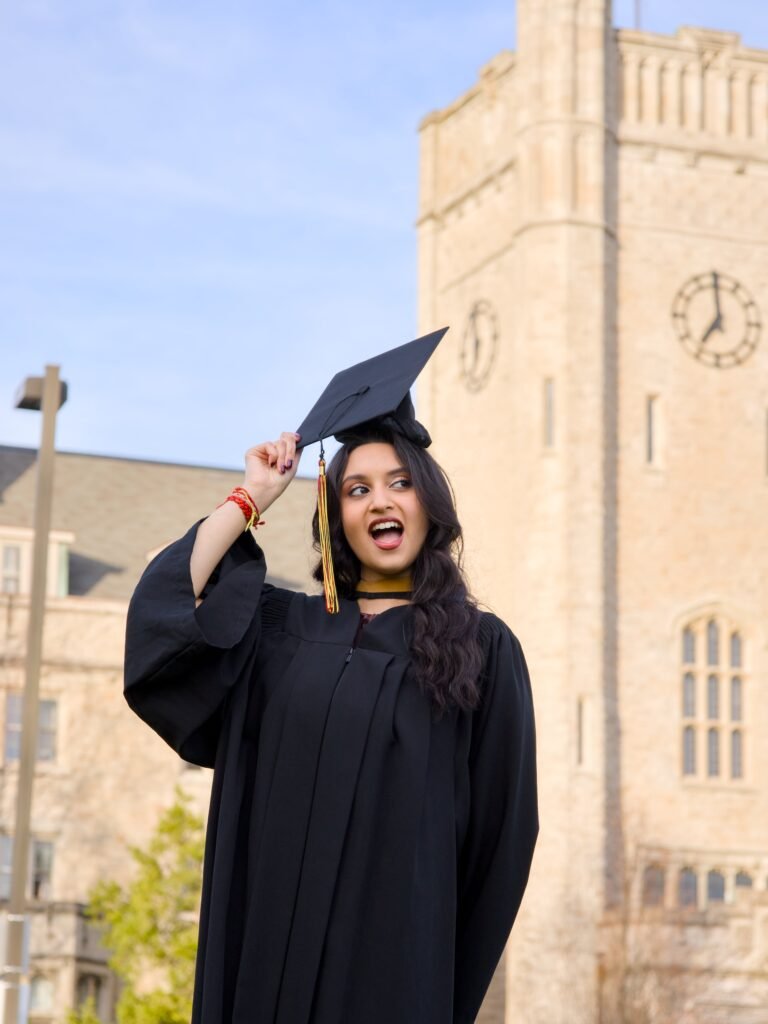 Graduate in black cap and gown posing in front of a clock tower. The photo is from Guelph Grad Photos. The background is the University of Guelph Campus.