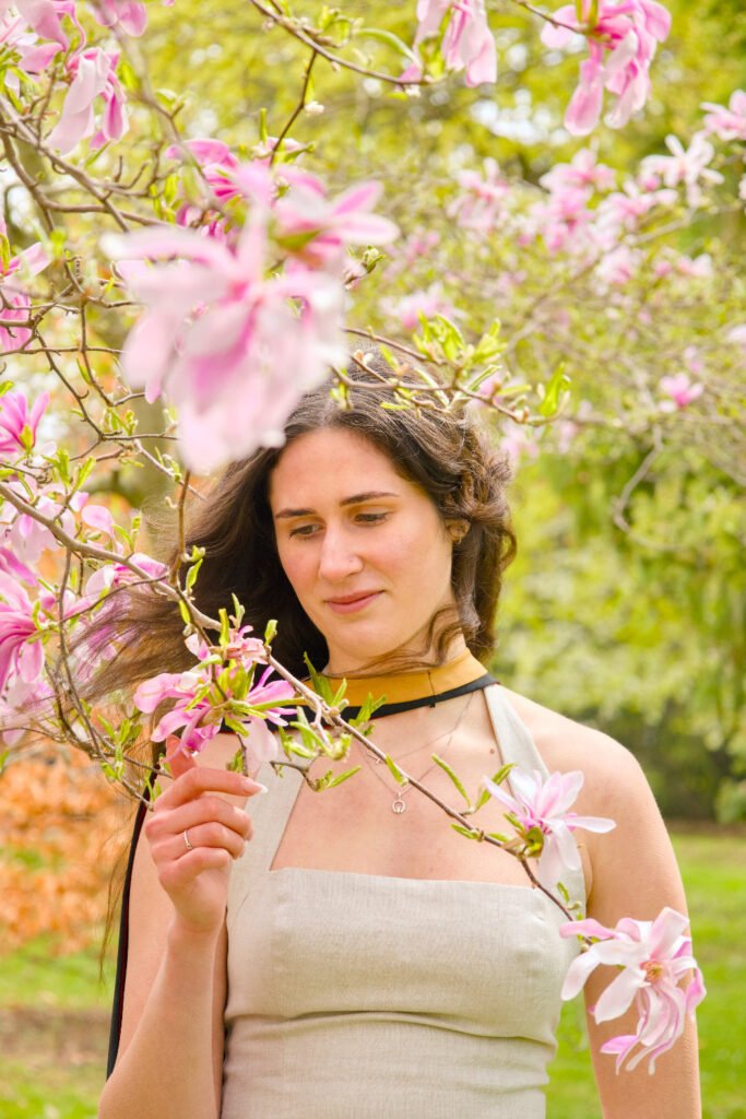 Woman standing among pink flowers in a garden. The photo is from Guelph Grad Photos. The background is the University of Guelph Campus.
