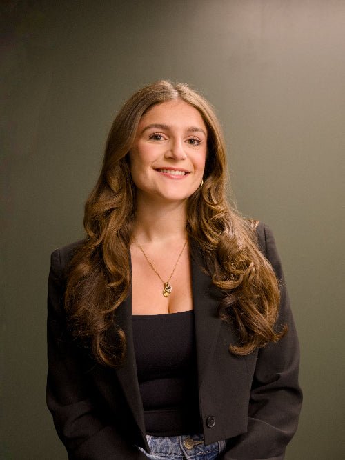 Woman with long brown hair wearing a black blazer against a gray background, LinkedIn headshots Guelph