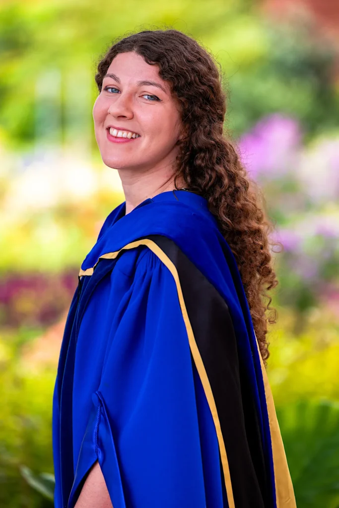 A University of Guelph graduate in doctoral regalia in the garden.