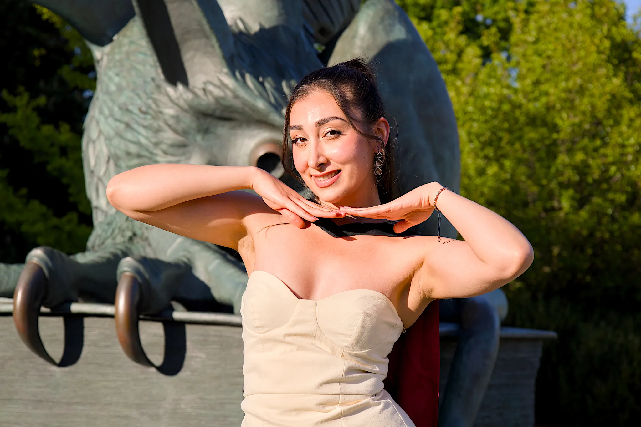 A University of Guelph graduate in regalia framing her face by the Gryphon statue.