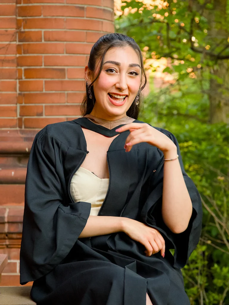 A University of Guelph graduate in regalia making a heart with her hands.