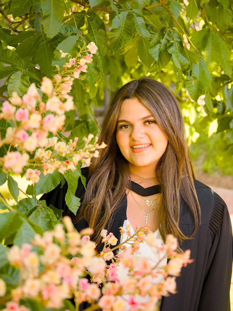 A University of Guelph graduate in regalia framed by pale blossom.