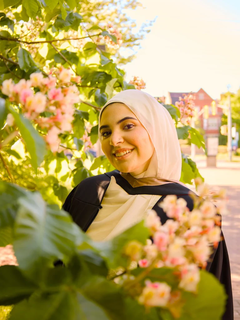 A University of Guelph graduate among the white blossom in a hijab and regalia.