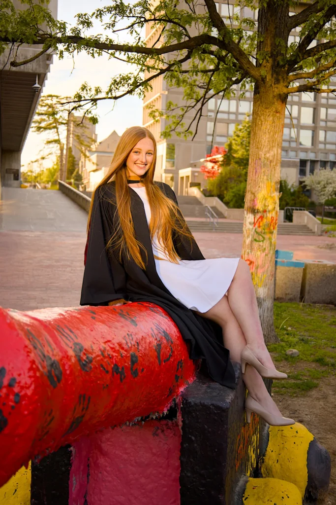 A University of Guelph graduate in regalia perched on the painted cannon.
